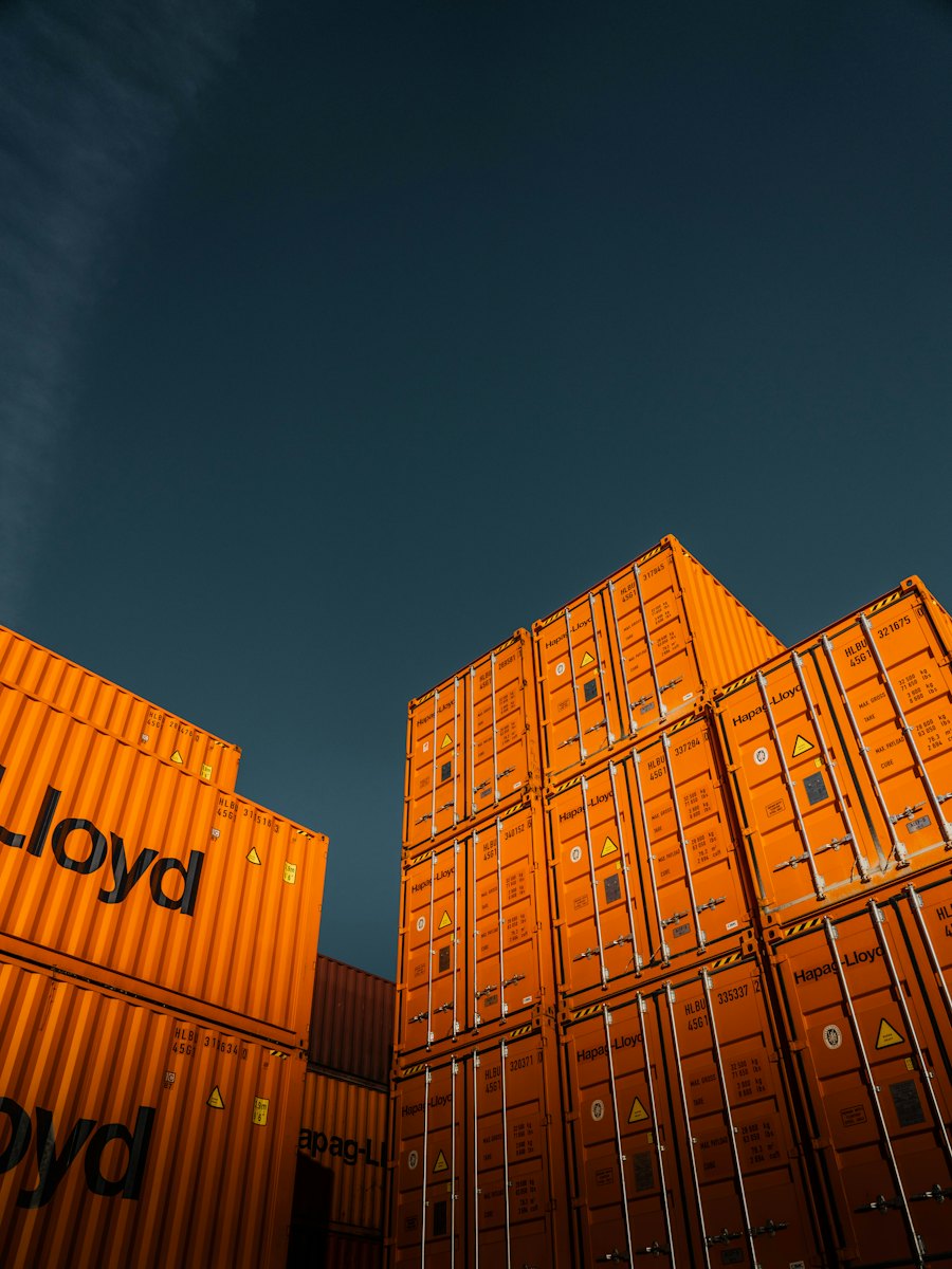 Stacked orange shipping containers against a deep blue sky